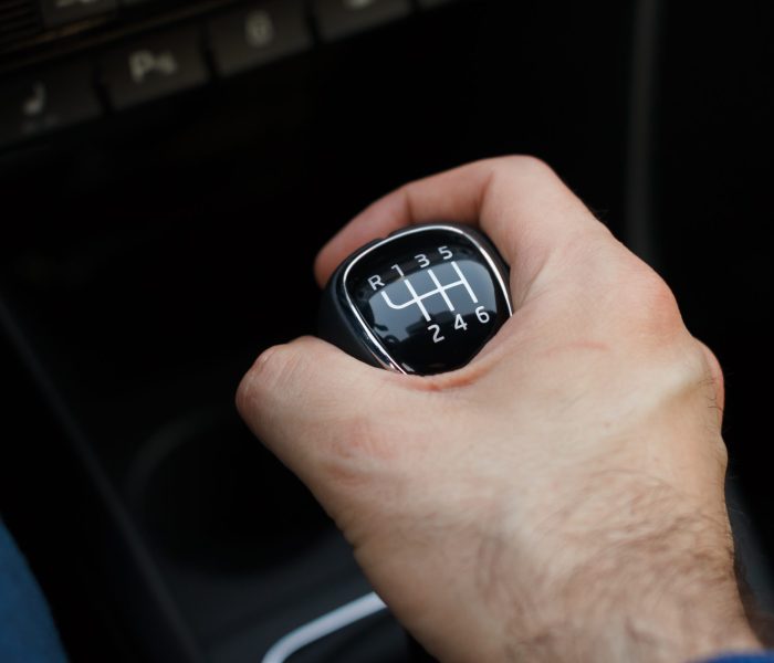 Man hand on a mechanical gearbox in the car. Man driving car. Car interior details. Car 6 speed transmission