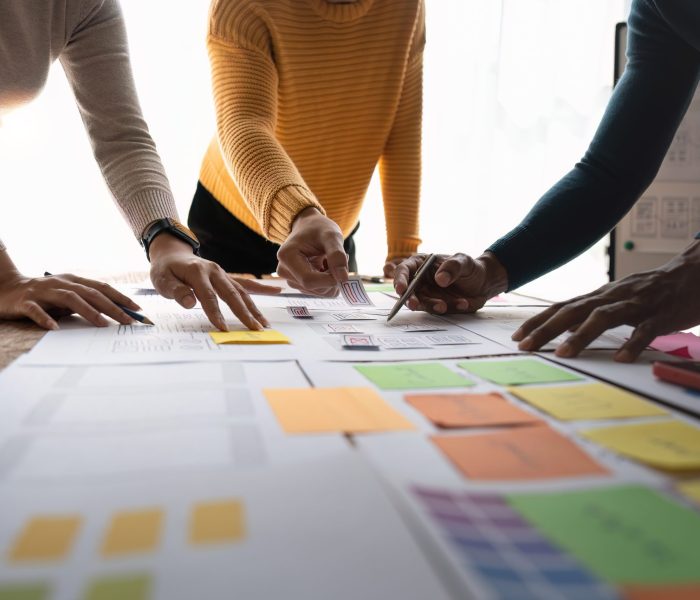 Close up ux developer and ui designer brainstorming about mobile app interface wireframe design on table with customer brief and color code at modern office.Creative digital development agency.panning.