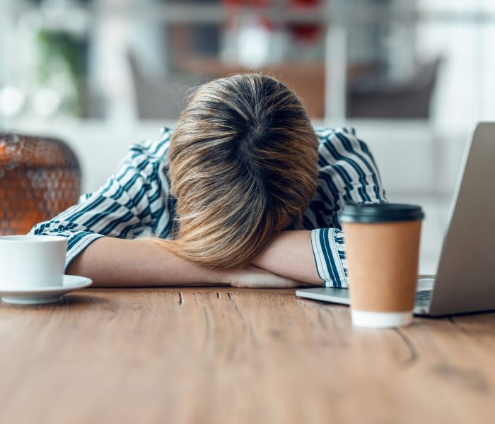 Shot of exhausted young business woman who has fallen asleep while working wirh laptop in living room at home.