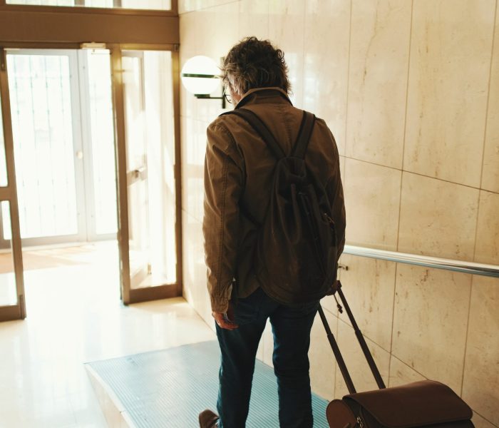 Middle aged man leaving home with luggage